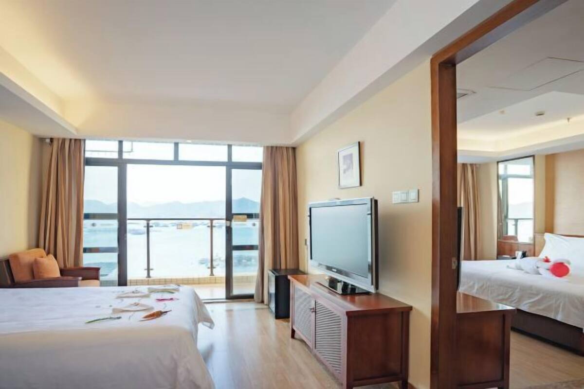 Una habitación de hotel con cama, televisor, escritorio y vista al mar.
