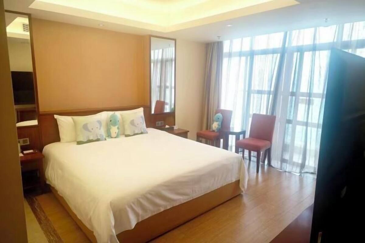 Una habitación de hotel con una cama grande, un escritorio, una silla y un televisor.