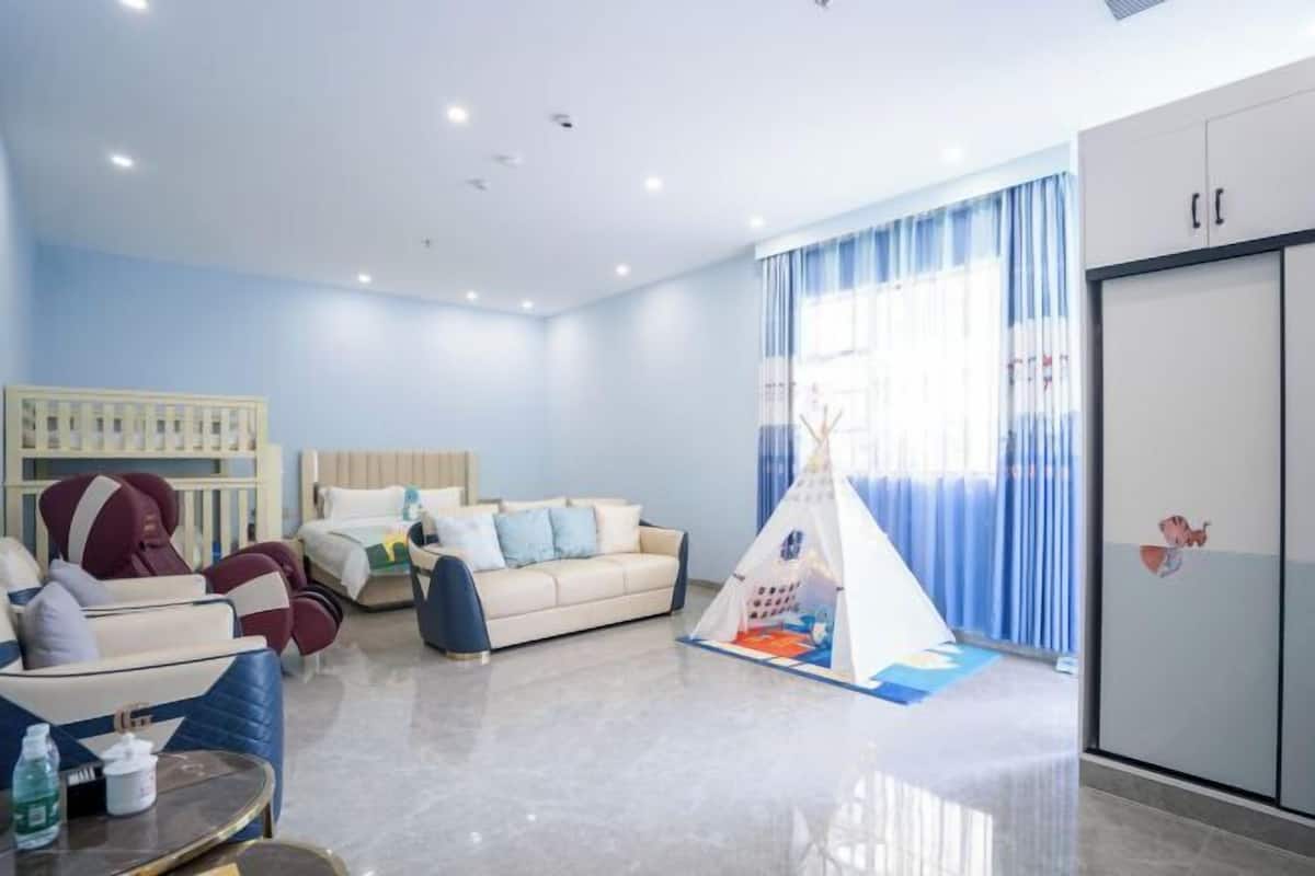 Una habitación de hotel moderna con sofá, cama, tienda de juegos y armario.