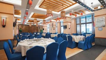 Un salón de banquetes con mesas redondas, sillas azules y techo de madera.