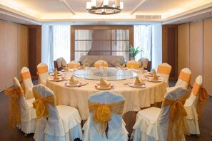 Une salle de conférence équipée d’une table ronde, de chaises et d’un lustre.