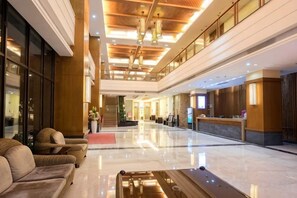Eine geräumige Lobby mit einer Rezeption, einer Sitzecke und einem glänzenden Boden.
