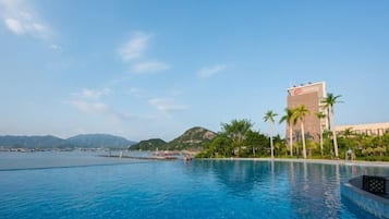 Una piscina con vistas a un edificio y montañas al fondo.
