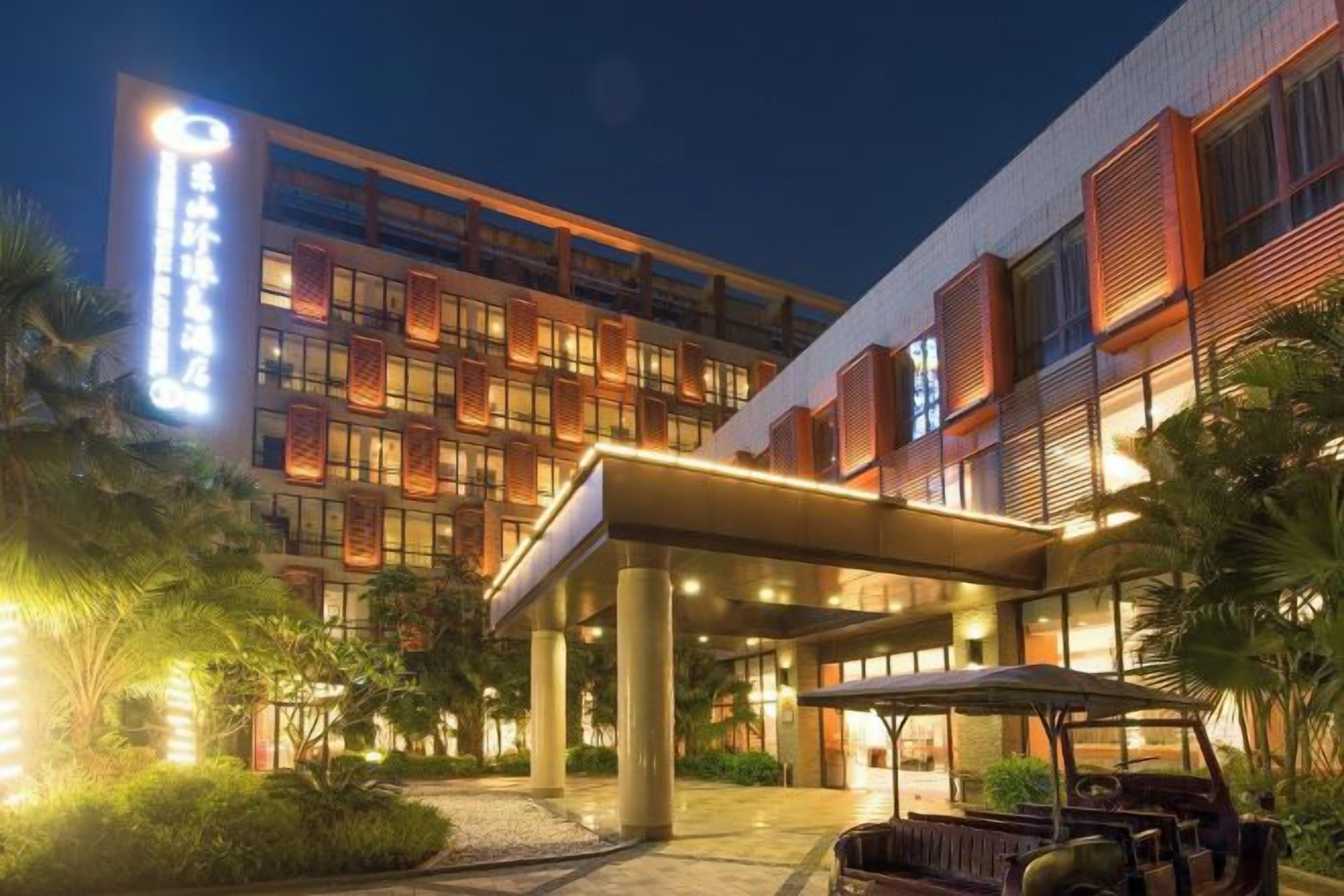 A hotel with a modern facade, a covered entrance, and a well-lit outdoor area with a golf cart.