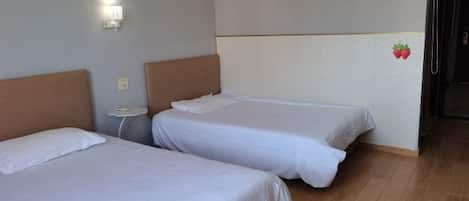A hotel room with two beds, a nightstand, a wall-mounted light, and a door.