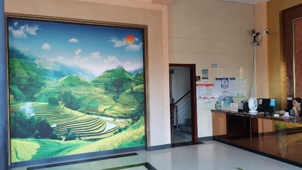 A reception area with a large mural of terraced fields, a reception desk, and a staircase leading to an upper floor. - Hai Shi Cheng Lou Business Hotel (Yuhuan)