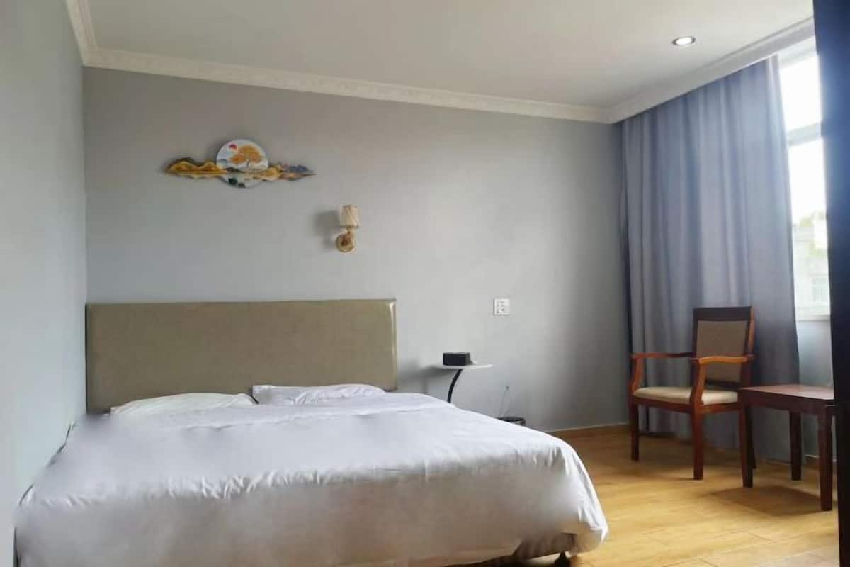Ein Hotelzimmer mit Bett, einem Sessel, einem kleinen Tisch und einer Wandleuchte.