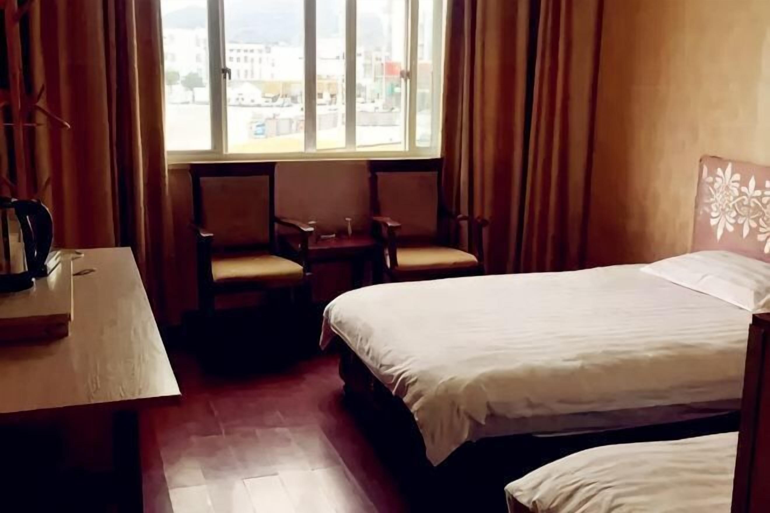 Una habitación de hotel con cama, dos sillas, una mesita y una ventana con cortinas.