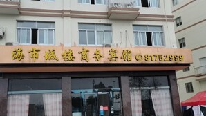 A hotel with a signboard displaying the name and contact number. - Hai Shi Cheng Lou Business Hotel (Yuhuan)