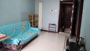 A room with a sofa, a small table, a cabinet, and a door leading to another room. - Shanghaojia Apartment (Zhengzhou Digital Harbor) (Zhengzhou)