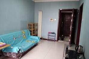 A room with a sofa, a small table, a cabinet, and a door leading to another room. - Shanghaojia Apartment (Zhengzhou Digital Harbor) (Zhengzhou)