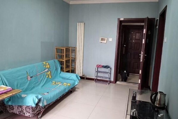 Una habitación con sofá, una mesita, un armario y una puerta que da a otra habitación.