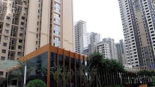 A modern building with a glass facade, surrounded by high-rise residential buildings. - Shanghaojia Apartment (Zhengzhou Digital Harbor) (Zhengzhou)