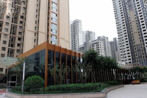 A modern building with a glass facade, surrounded by high-rise residential buildings. - Shanghaojia Apartment (Zhengzhou Digital Harbor) (Zhengzhou)