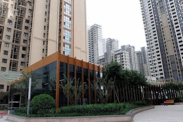 A modern building with a glass facade, surrounded by high-rise residential buildings. - Shanghaojia Apartment (Zhengzhou Digital Harbor) (Zhengzhou)
