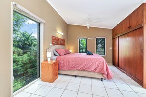 Une chambre à coucher avec un lit, une table de chevet, une armoire et de grandes fenêtres.