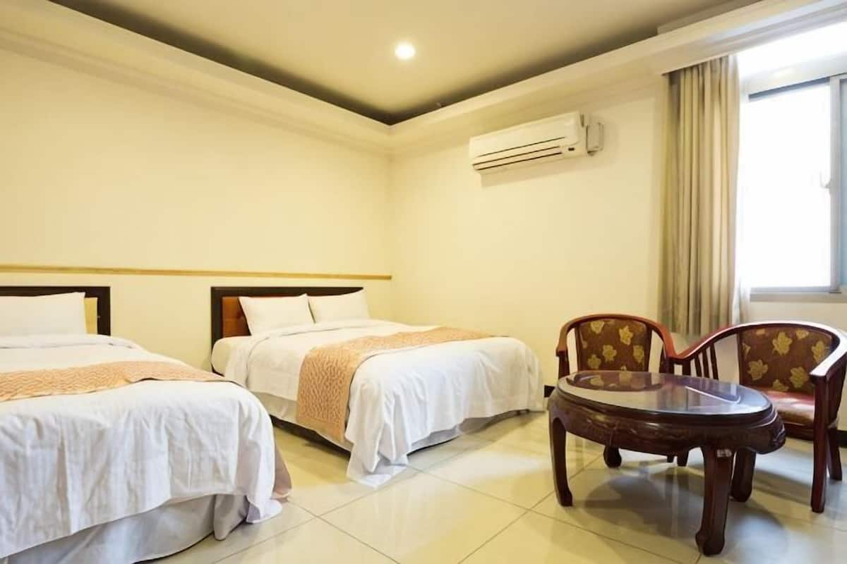 A hotel room with two beds, a round table, and two chairs.
