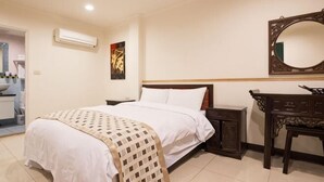 Camera d'albergo con un letto, un comodino, una cassettiera e uno specchio a parete.
