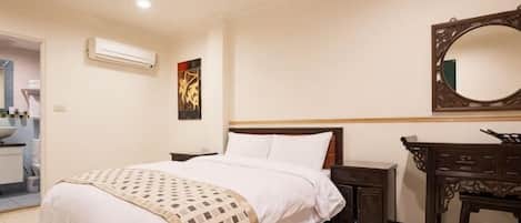 A hotel room with a bed, bedside table, dresser, and a mirror on the wall.