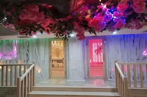 Una escalera con barandillas de madera que conduce a una habitación con pared de mármol y una puerta decorativa.