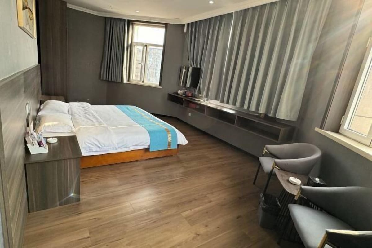 Ett modernt hotellrum med en säng, ett sängbord, en TV och en sittgrupp.