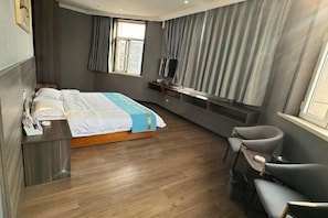 Ett modernt hotellrum med en säng, ett sängbord, en TV och en sittgrupp.