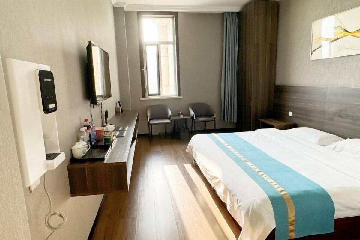 Una habitación de hotel con cama, escritorio, silla, televisor y ventana.