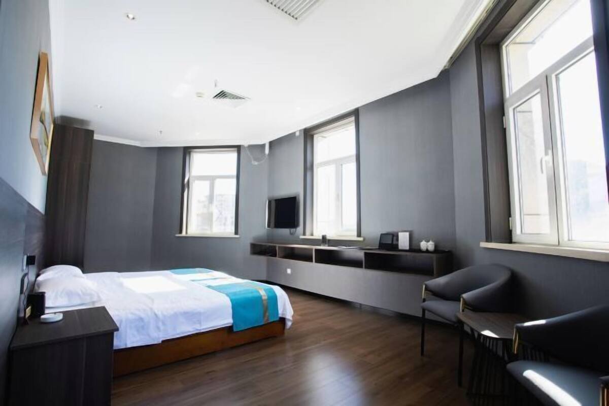 Una habitación de hotel moderna con cama, televisor, escritorio y silla.