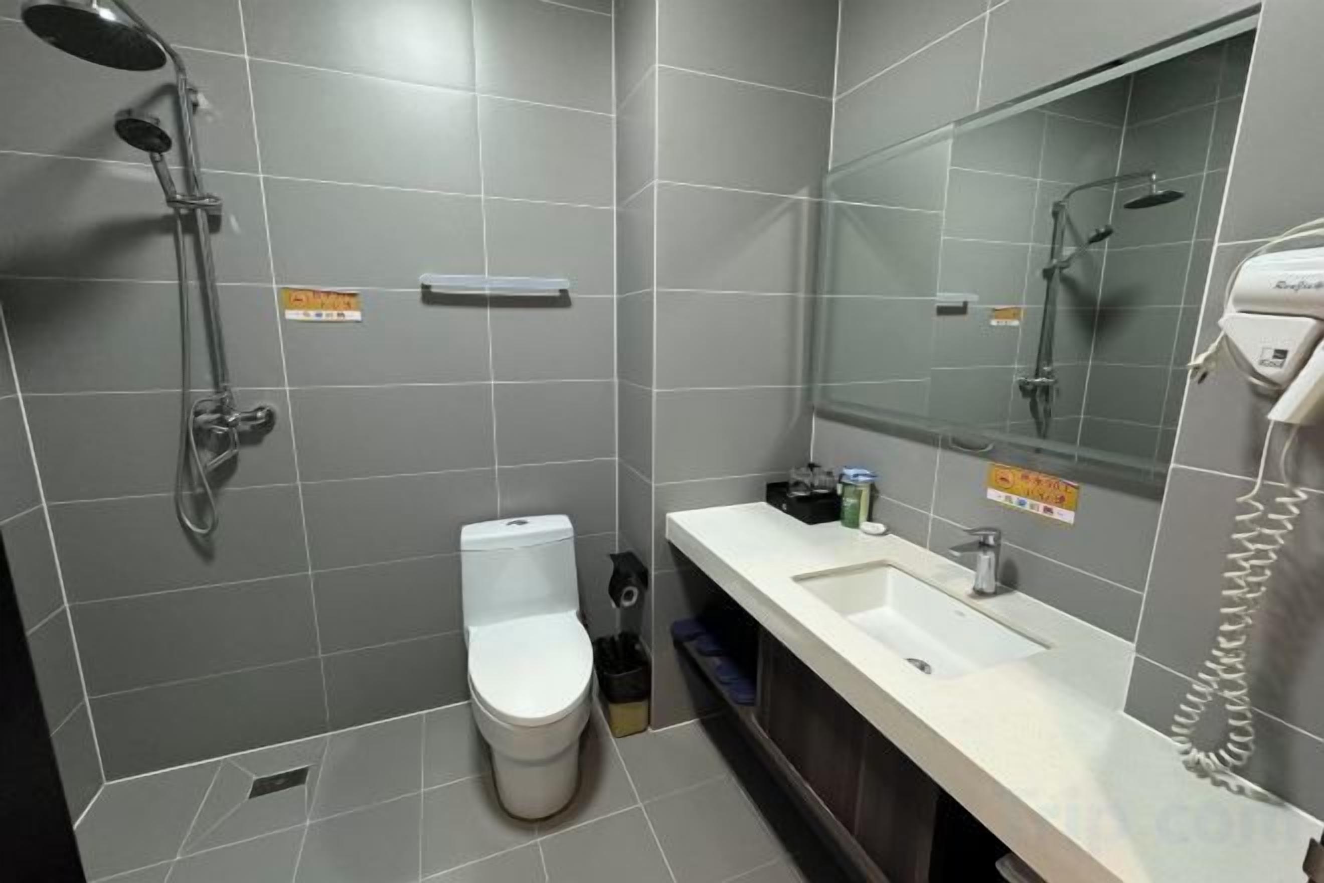 A bathroom with a toilet, sink, and shower.