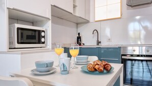 A modern kitchen with a microwave, oven, and breakfast setup including croissants and orange juice. - Vela Azul  • A/C, Pool & Tennis (Puerto del Carmen)