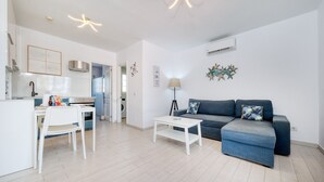A modern living room with a white dining table, a blue sofa, and a white coffee table. - Vela Azul  • A/C, Pool & Tennis (Puerto del Carmen)