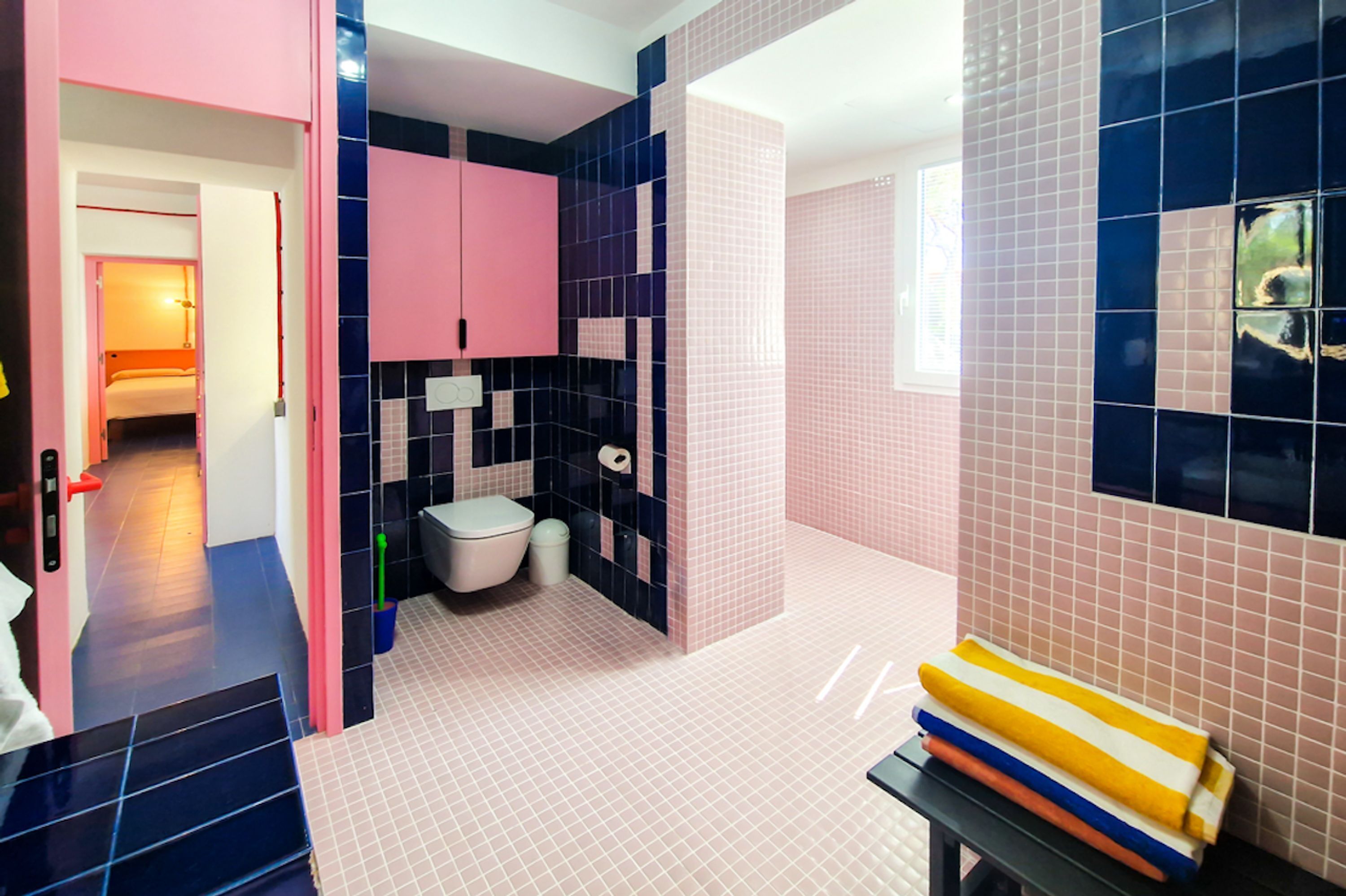A modern bathroom with a pink and blue color scheme, a toilet, and a sink.