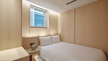 A modern bedroom with a wooden headboard, a bedside table with a lamp, and a large bed.
