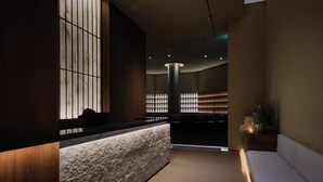 A reception area with a reception desk, a seating area, and a wall with vertical blinds. - UH Suite The Gangnam (Seoul)