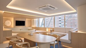 A modern hotel room with a large window, a bathtub, a dining area, and a TV. - UH Suite The Gangnam (Seoul)