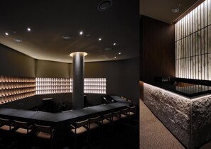 A modern interior with a central table, chairs, recessed ceiling lights, and a decorative wall with vertical panels. - UH Suite The Gangnam (Seoul)