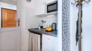 A kitchen with a microwave, sink, and a clock on the wall.