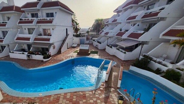 A modern resort with a central swimming pool surrounded by white buildings with red roofs and balconies. - Las Floritas 3 (Playa de Las Americas)