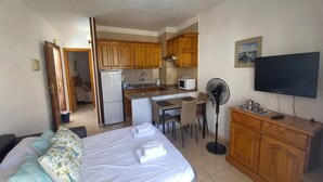 A compact hotel room with a bed, a small kitchenette, a dining area, and a TV. - Las Floritas 3 (Playa de Las Americas)