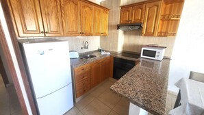A kitchen with wooden cabinets, a refrigerator, a microwave, and a dishwasher. - Las Floritas 3 (Playa de Las Americas)