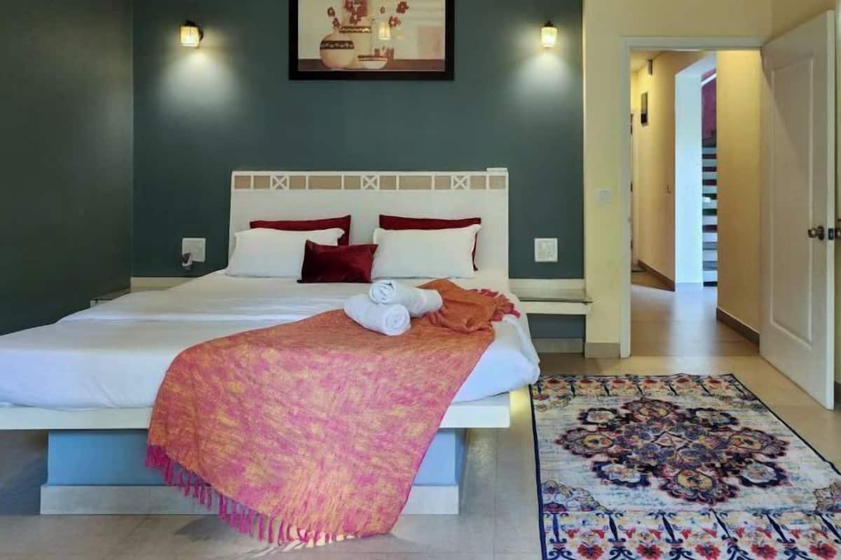 A bedroom with a bed, pillows, a blanket, and a rug.