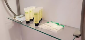 A bathroom shelf with various ECO amenities including conditioner, body wash, and shampoo. - Catskill Retreat (Hamden)