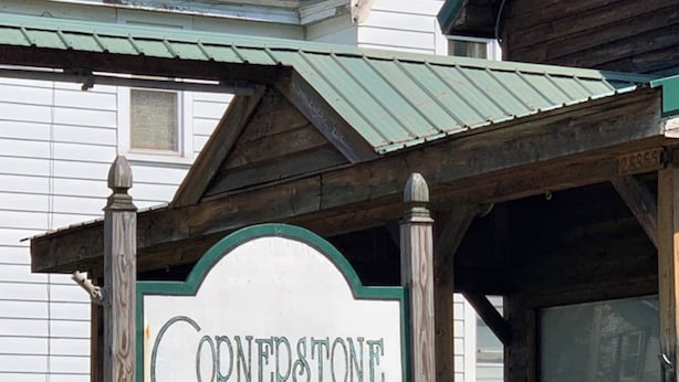 Ein Schild für Cornerstone Antiques vor einem Gebäude mit einem begrünten Dach.