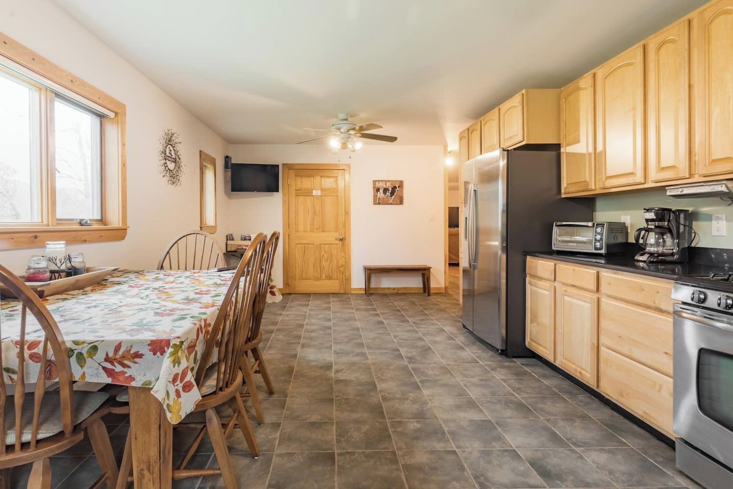 Una cocina con armarios de madera, un refrigerador, un microondas y una mesa de comedor con sillas.