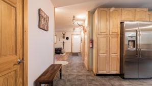 Eine Küche mit Holzausstattung, einem Edelstahlkühlschrank und einem Fliesenboden.