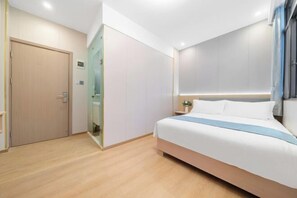 Ein Hotelzimmer mit Bett, Tür, Spiegel und Nachttisch.