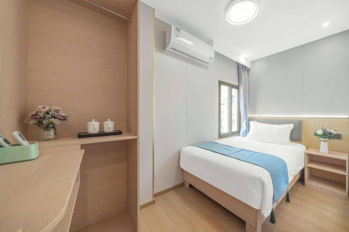 Una habitación de hotel con cama, mesita de noche y ventana.