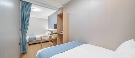 A hotel room with a bed, a desk, a chair, a wardrobe, and an air conditioning unit.