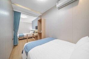 Ein Hotelzimmer mit Bett, Schreibtisch, Stuhl, Kleiderschrank und Klimaanlage.