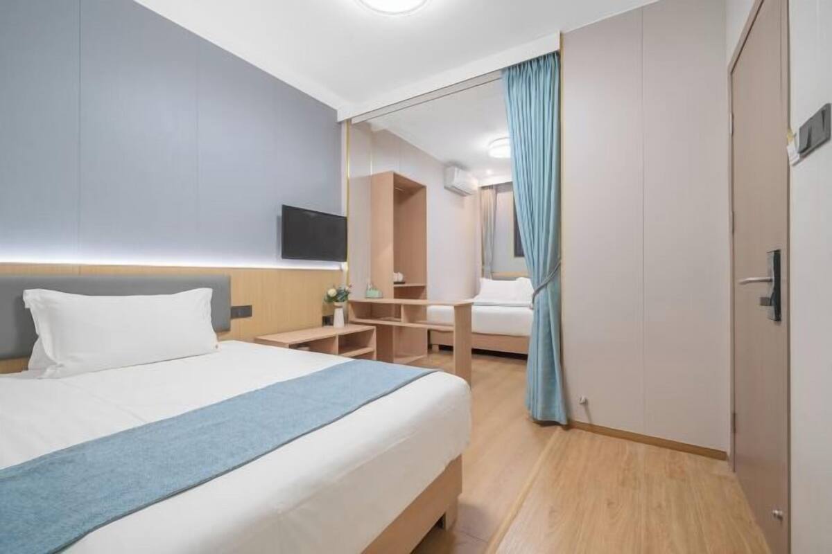 Habitación de hotel con cama, mesita de noche, televisor y espejo.